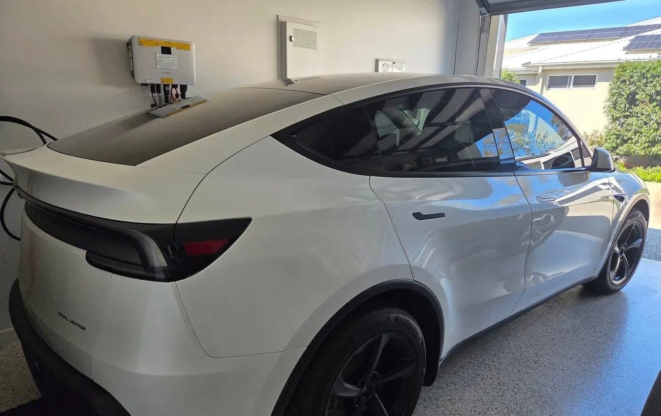 Tesla charging from a wall-mounted EV charger installed in a home garage