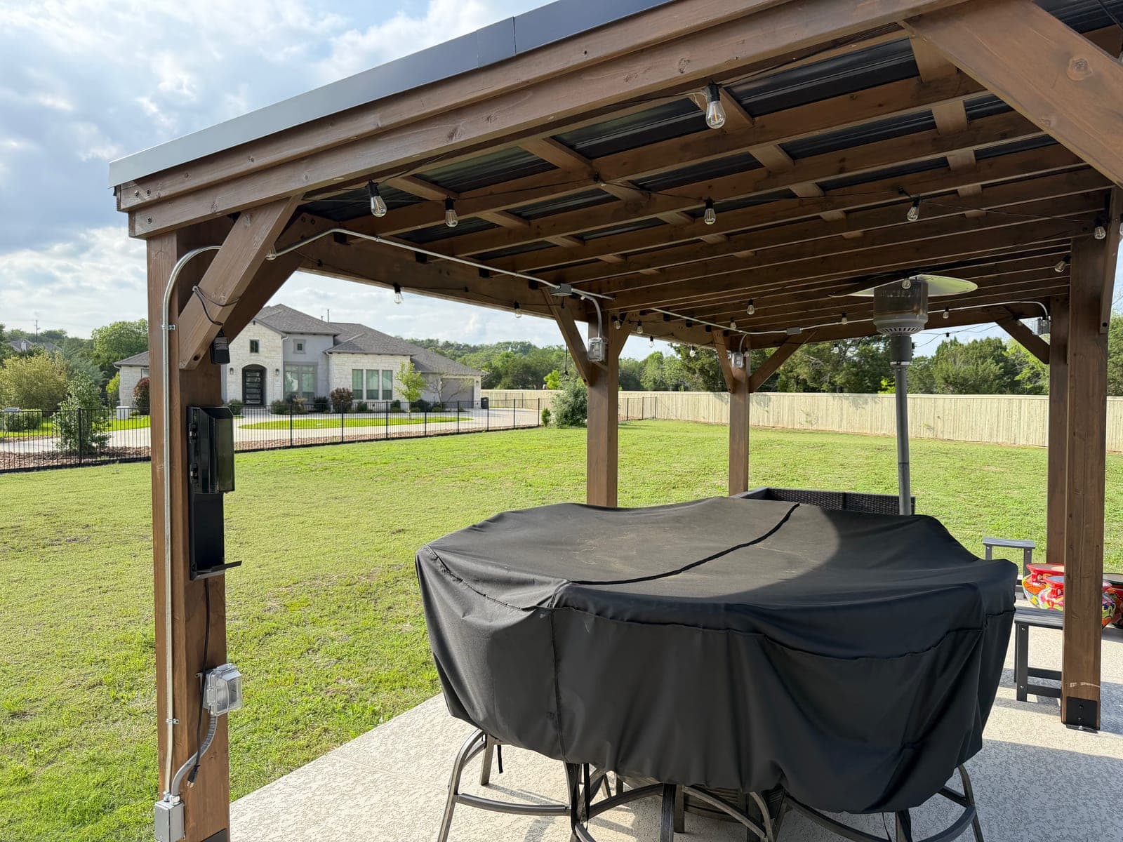 Backyard pergola with installed string lighting at dusk